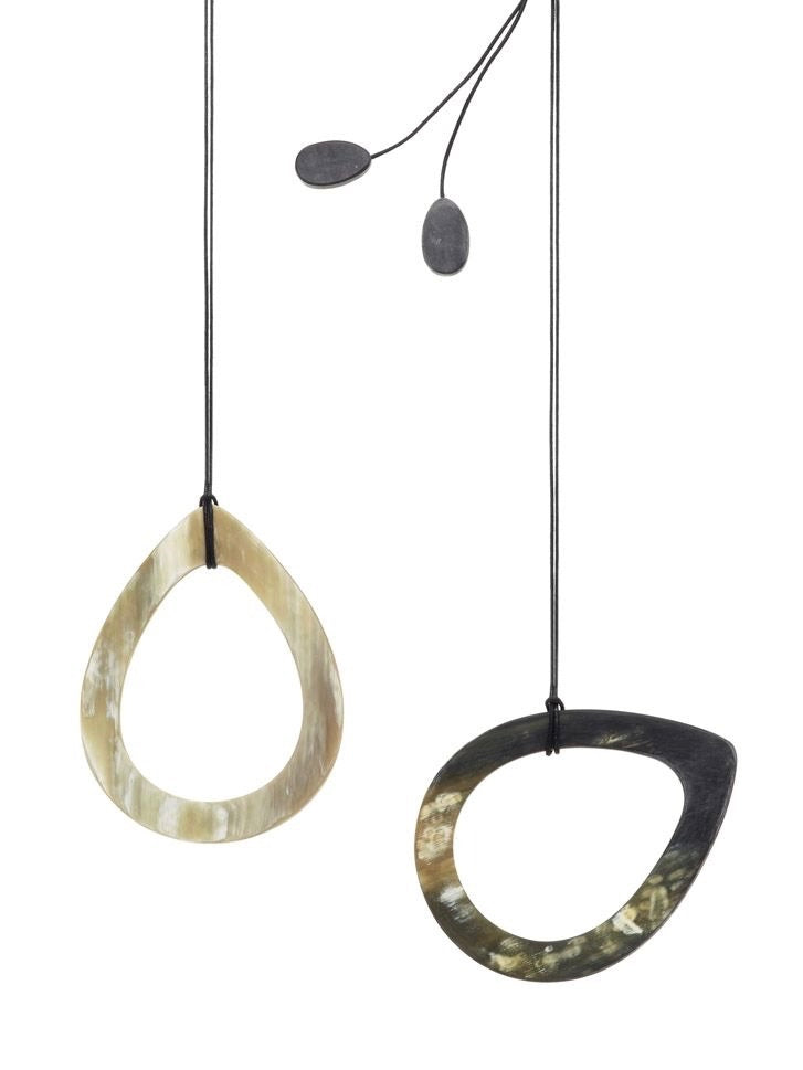 Large teardrop shape of matte black and white horn, hanging from a black cotton cording, by designer Cath S.