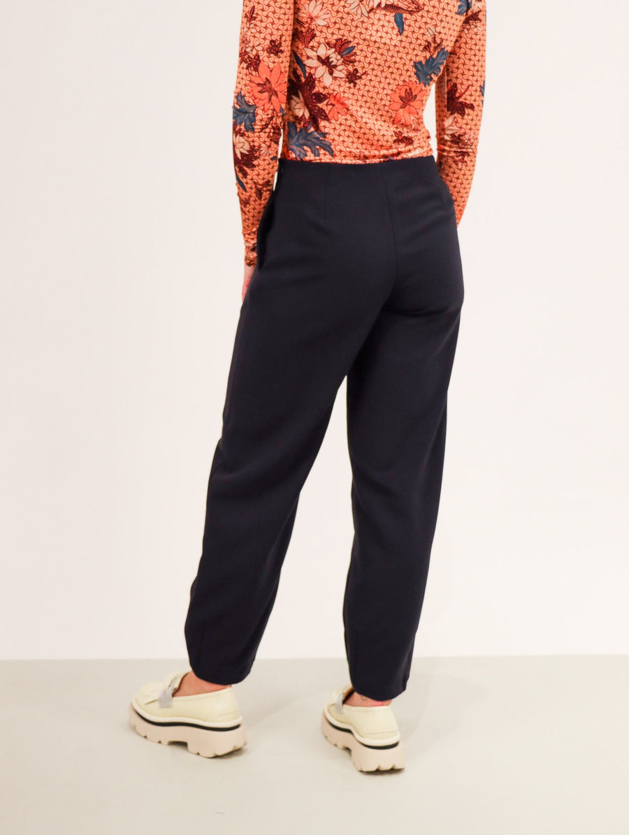 Midnight colored trousers with a straight let that ends in a tapered elastic cuff.