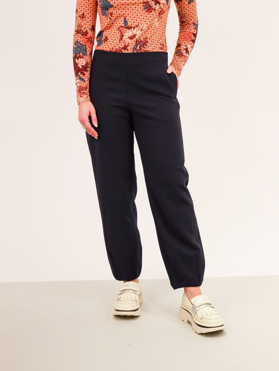 Midnight colored trousers with a straight let that ends in a tapered elastic cuff.