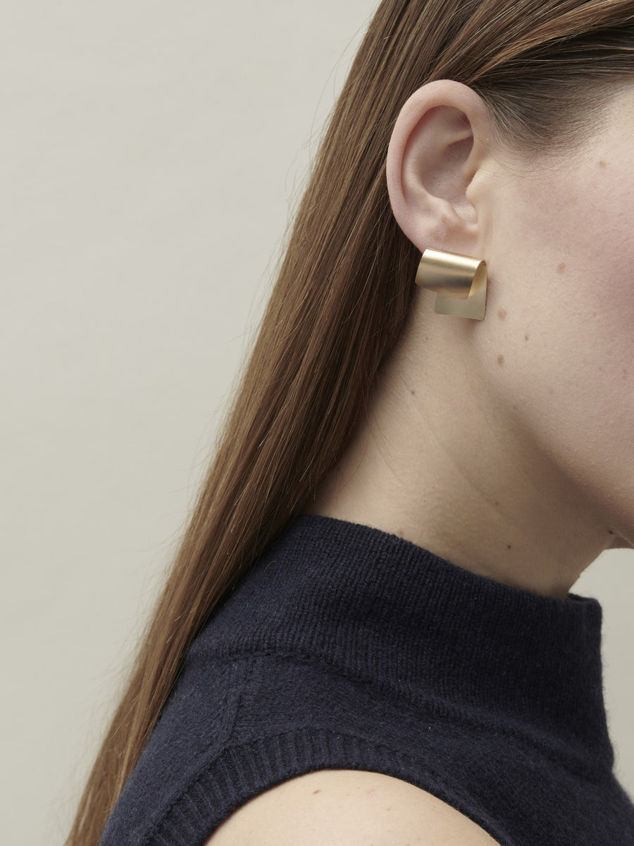 Earrings made from a small rectangle of folded gold-coated bronze, set on a post.