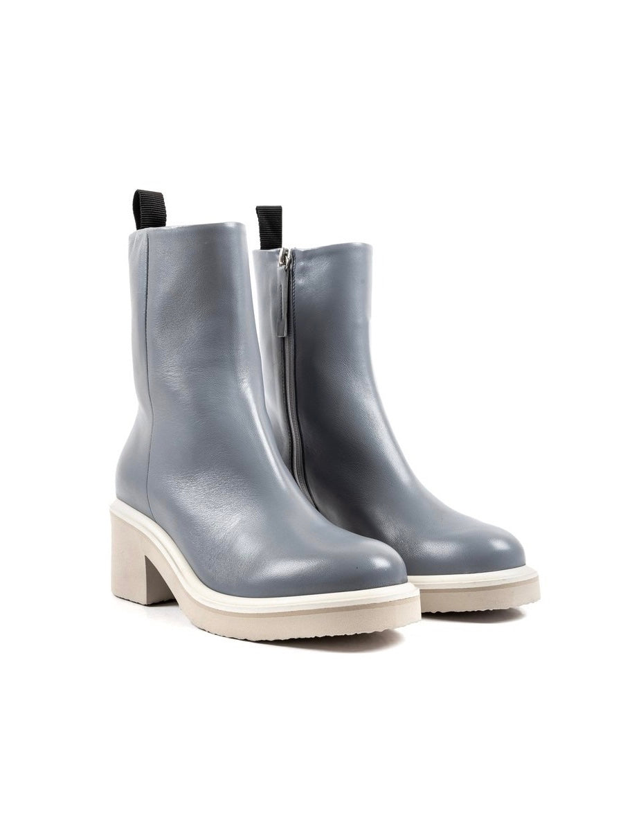 Slate blue demi boot with a heeled taupe foam sole, topped with a layer of rubber, and off-white welting.